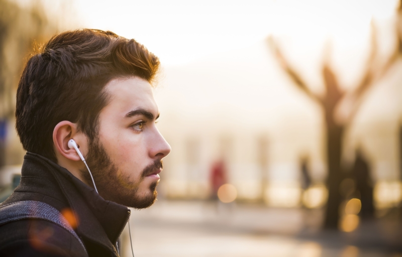 Mann mit Kopfhörern hört ein Audiobuch, um neue Impulse für das Glücklichsein bekommen